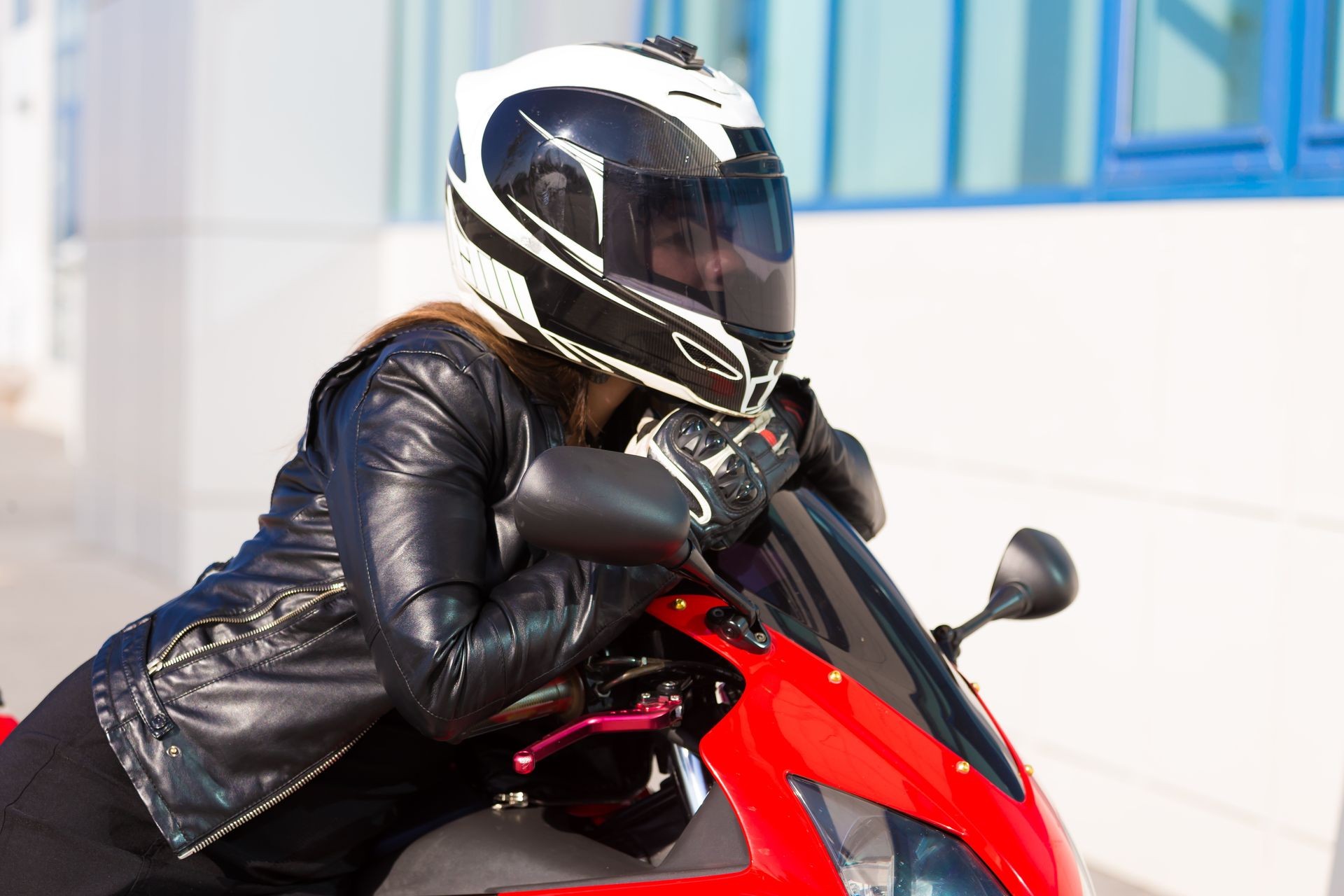 Beautiful woman driver, dressed in black jacket, helmet, riding on red motorcycle. Amazing sport portrait. Urban city fashion. Adventure travel hobby. Happy summer. Close up Beautiful woman driver, dressed in black jacket, helmet, riding on red motorcycle. Amazing sport portrait. Urban city fashion. Adventure travel hobby. Happy summer. Close up